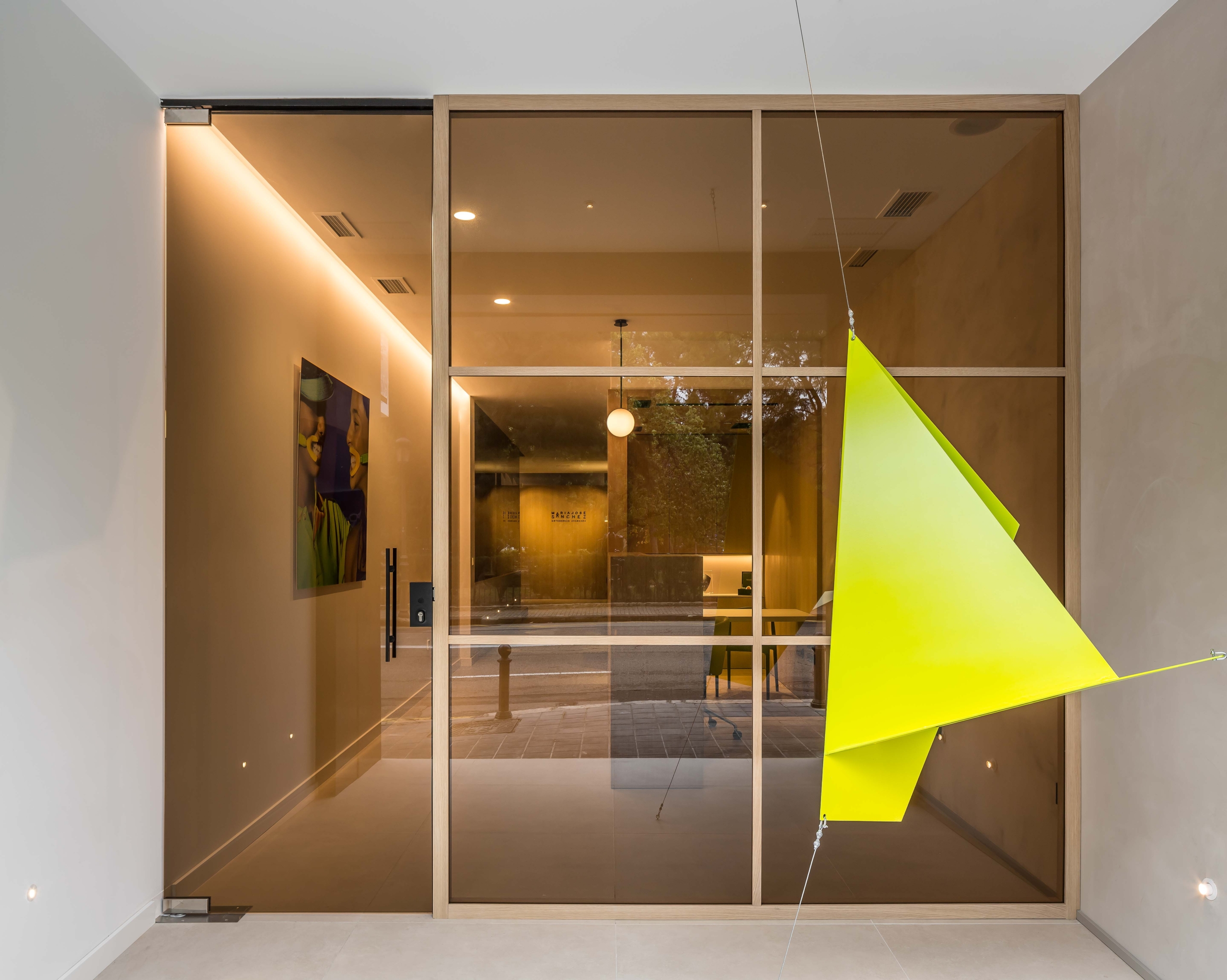 Puerta exterior con mobiliario artistico a la derecha con forma geometrica, con puerta de cristal opaca