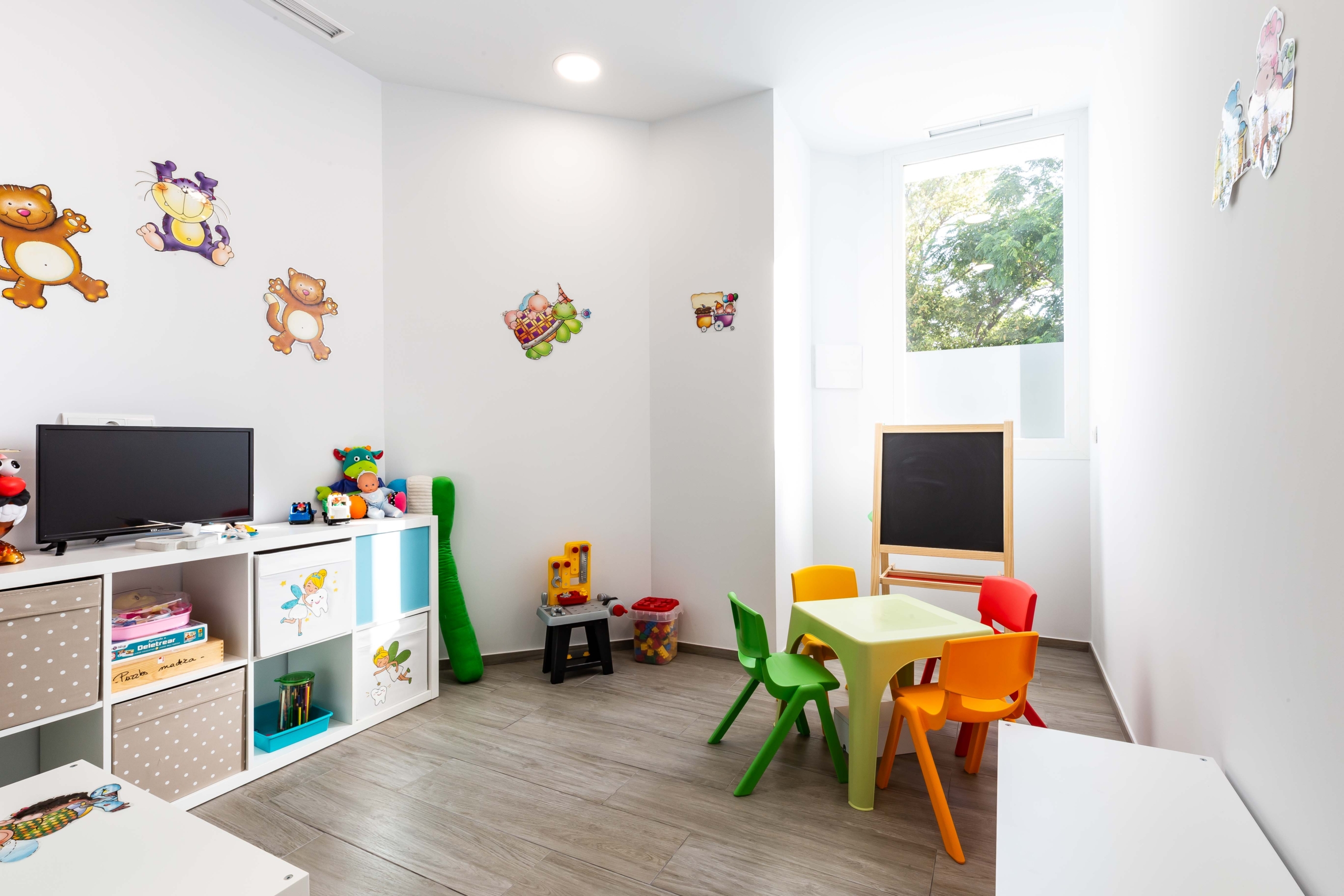 Sala de estar infantil para el dentista con jueguetes y pantallas para ver dibujos
