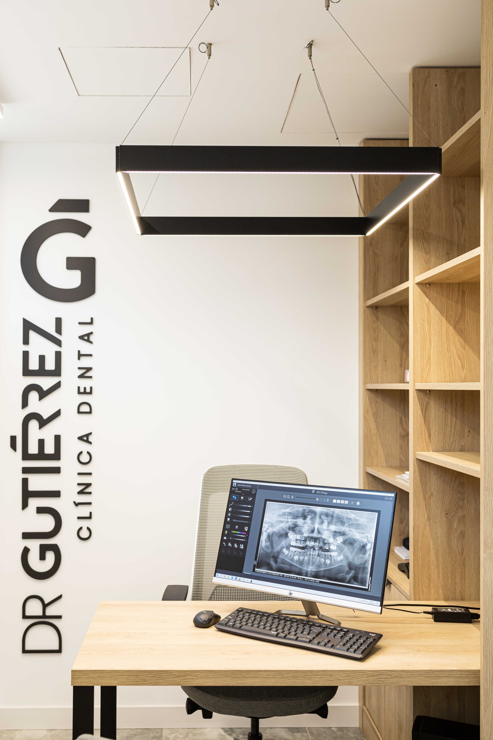 Sala de reuniones con acabado en madera y con ordenador y diseño logo con nombre ¨Dr Gutierrez¨