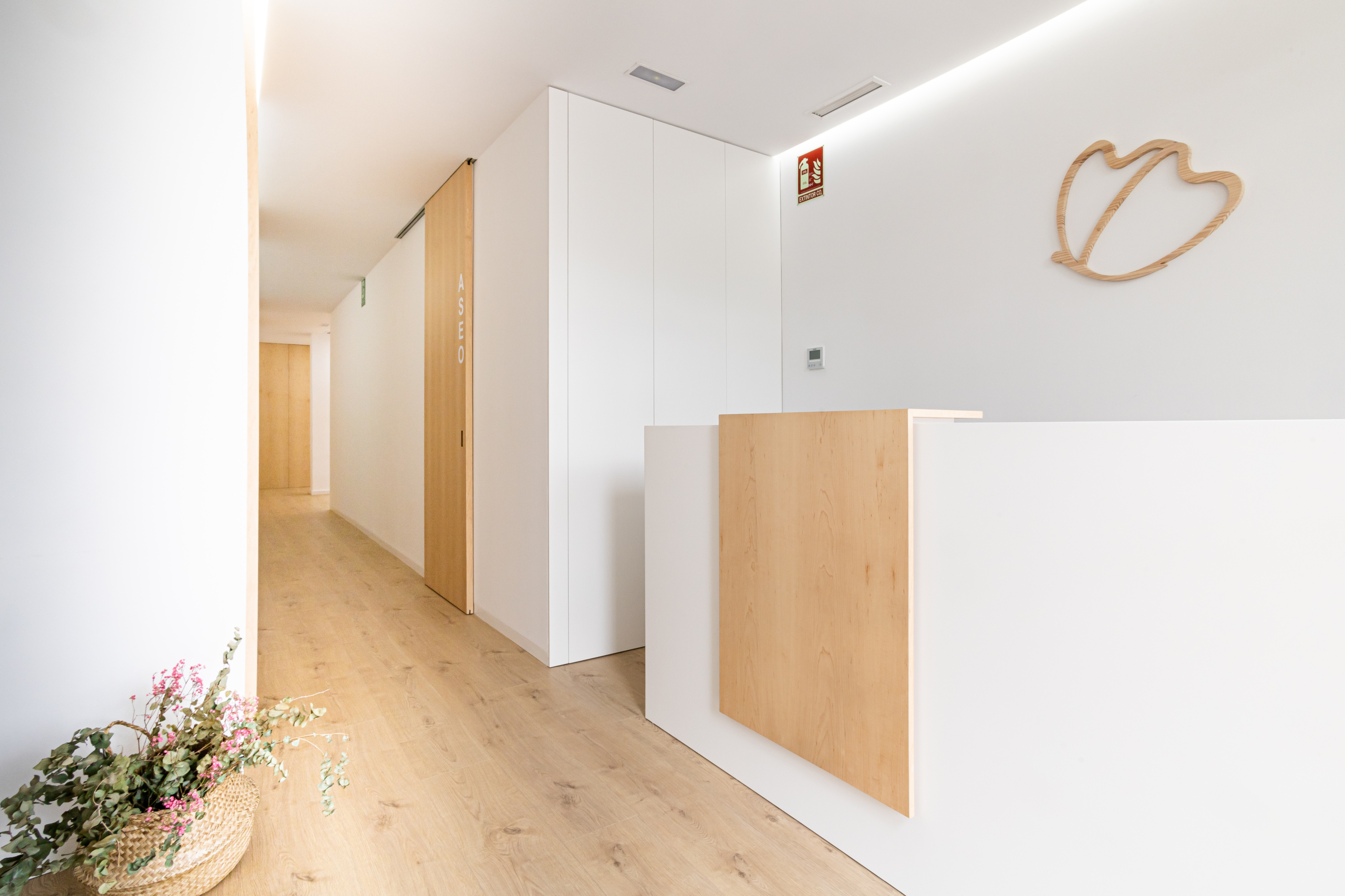 Sala de consulta con pasillo en acabado moderno, con color blanco y madera