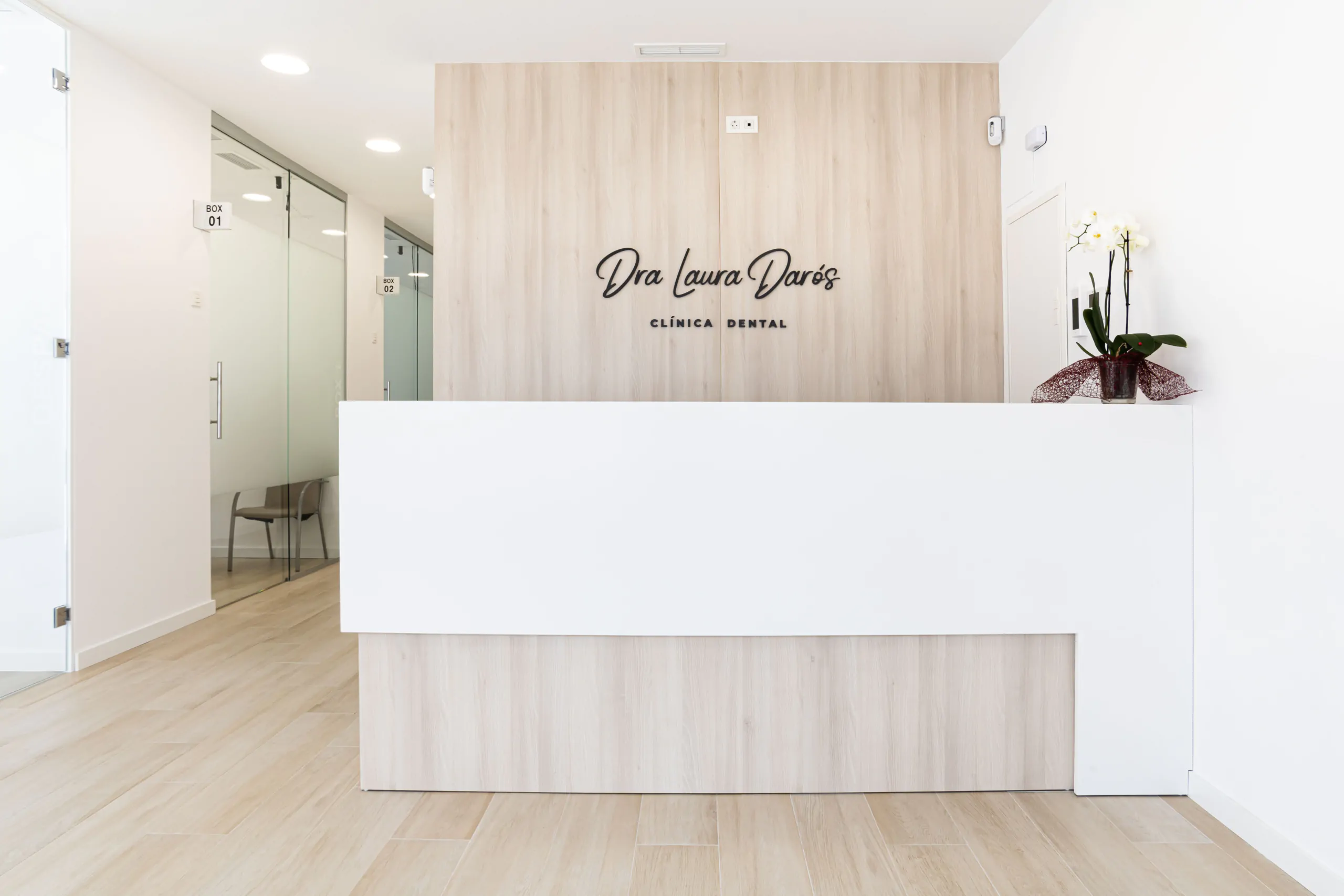 Sala de recepcion con acabados blancos y de madera con el nombre ¨Dra Laura Daros¨