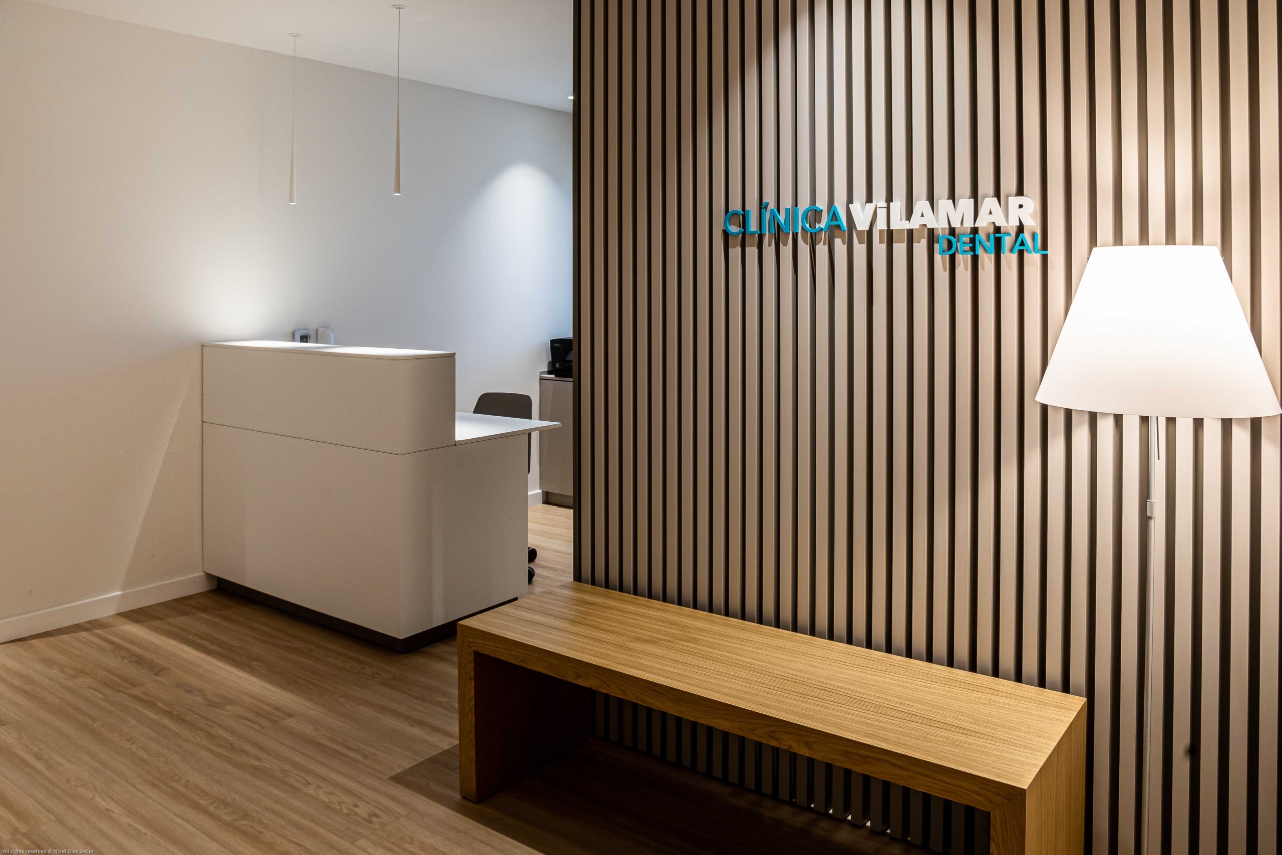 Sala de recepcion con nombre Clinica Vilamar con acabados blancos y de madera