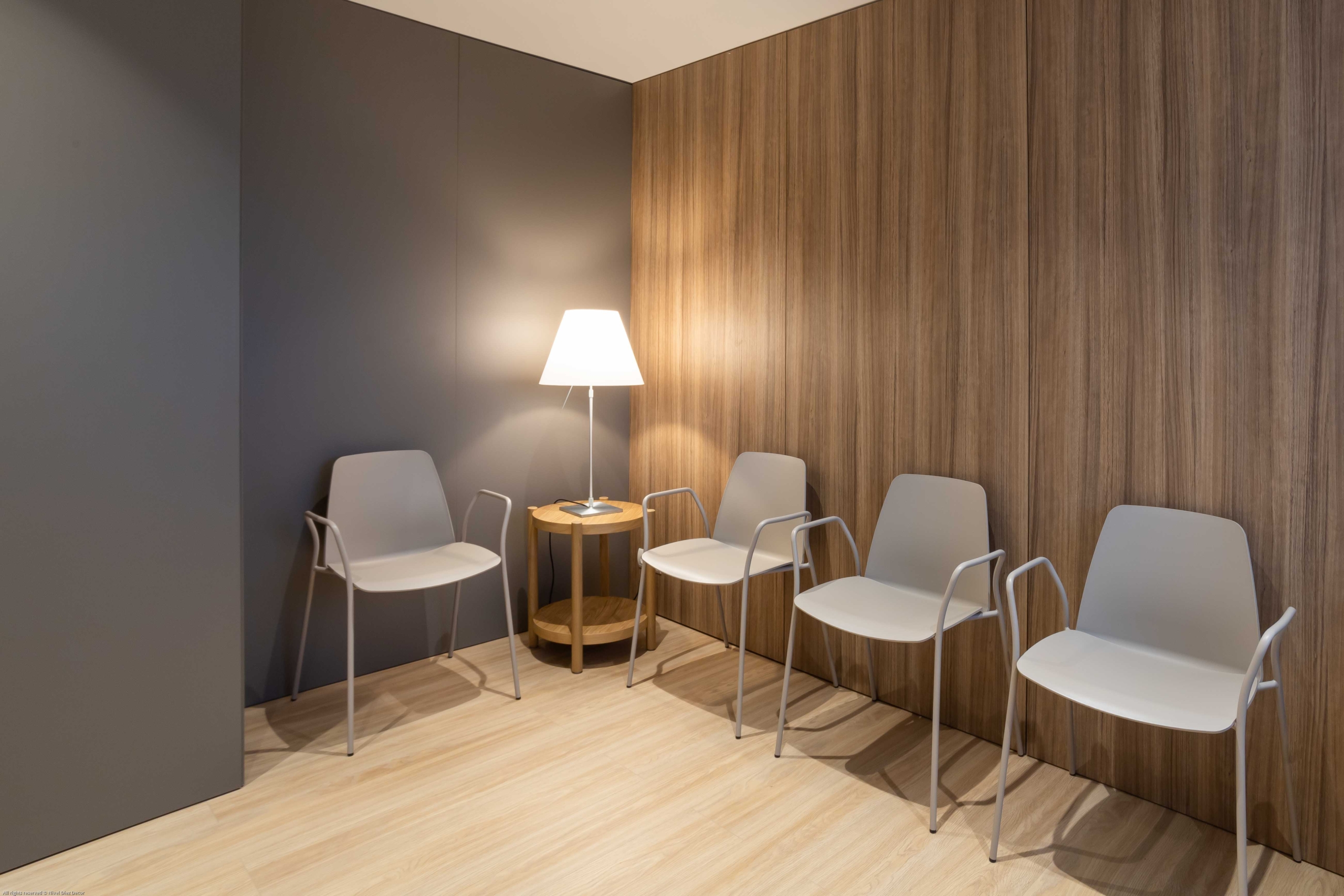 Sala de recepción con sillas y lampara en blanco y acabado de madera