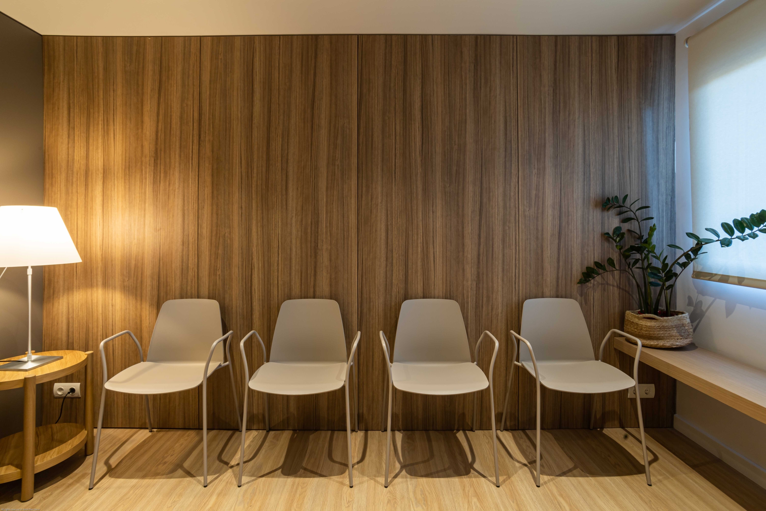 Sala de recepción con sillas y lampara en blanco y acabado de madera