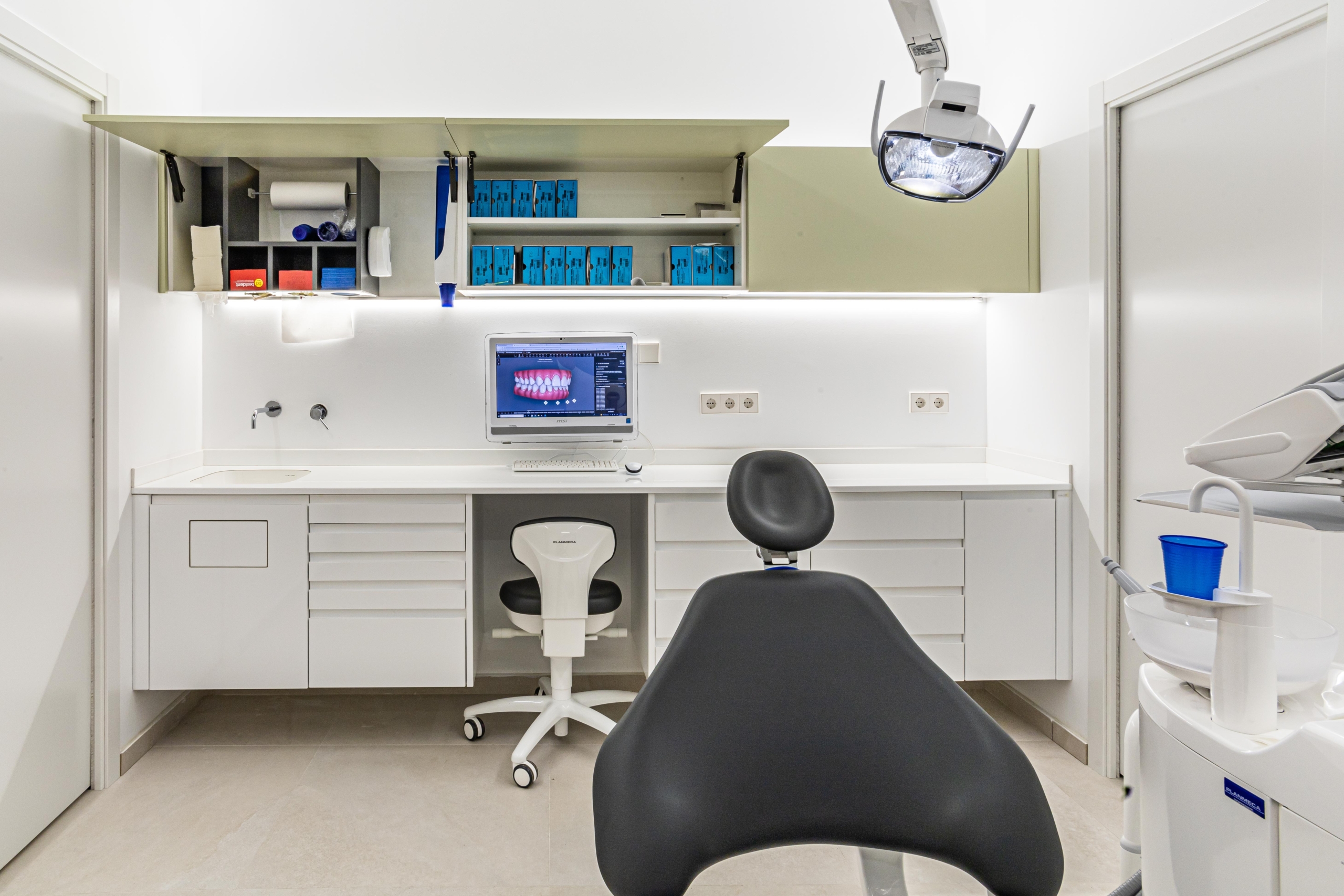 Mobiliario protesico con encimera blanca, mueble dispensador, ordenador y silla odontologica con acabado en negro